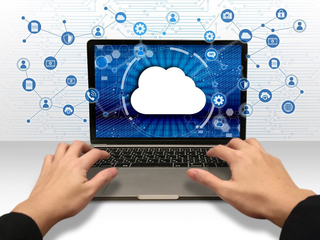 Hands using a laptop with a cloud icon on screen